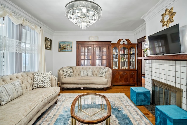 living area with a fireplace, a chandelier, crown molding, and wood finished floors