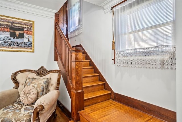 stairs featuring baseboards, wood finished floors, and crown molding