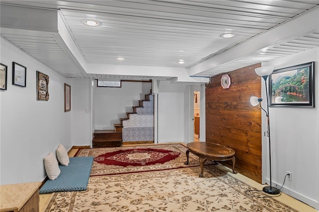 finished basement with stairs, wooden walls, recessed lighting, and baseboards