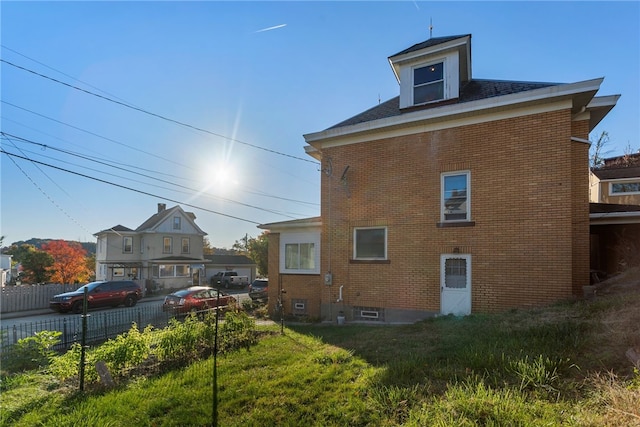 exterior space featuring brick siding, a lawn, and fence