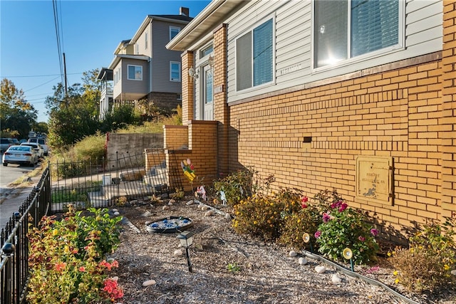 view of side of property with brick siding and fence