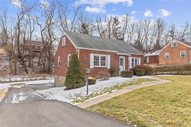 view of front of home with brick siding, a yard, and a chimney