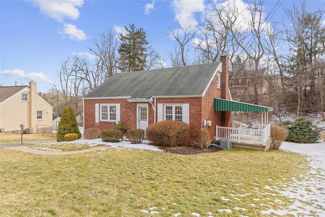 view of front facade featuring brick siding, a front lawn, and a chimney