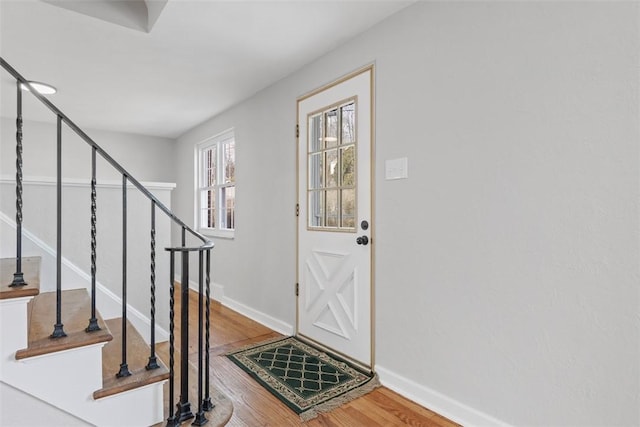 foyer featuring baseboards, stairway, and wood finished floors