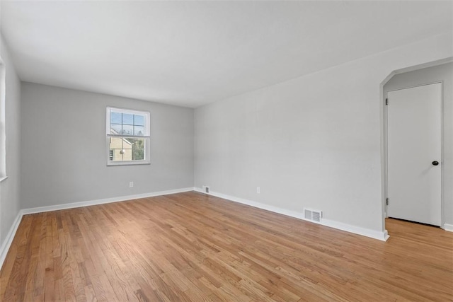 empty room with light wood-style floors, visible vents, and baseboards