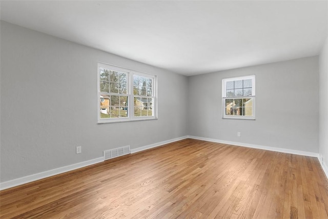 unfurnished room featuring light wood-type flooring, visible vents, and baseboards