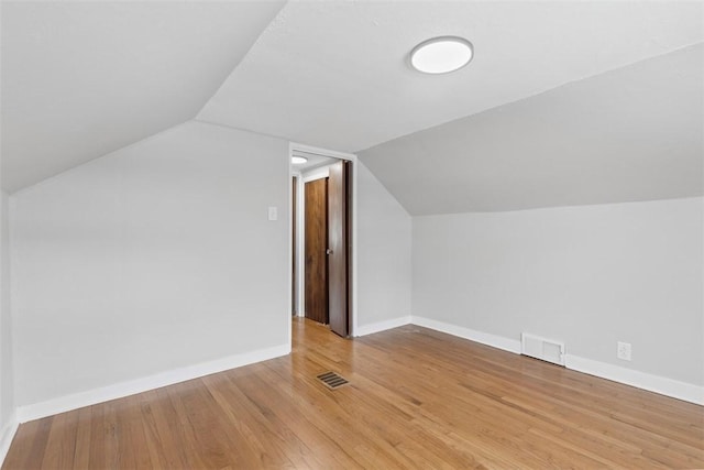 additional living space featuring lofted ceiling, wood finished floors, visible vents, and baseboards