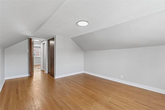 bonus room with vaulted ceiling, light wood-type flooring, and baseboards