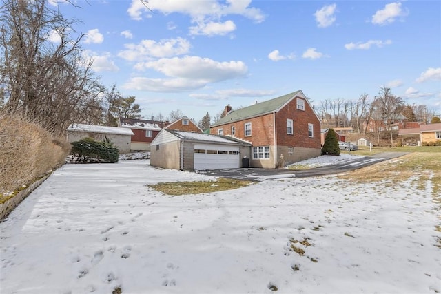 view of front of home featuring a garage, a residential view, brick siding, and an outdoor structure