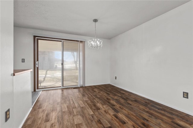 unfurnished dining area with an inviting chandelier, baseboards, dark wood finished floors, and a textured ceiling