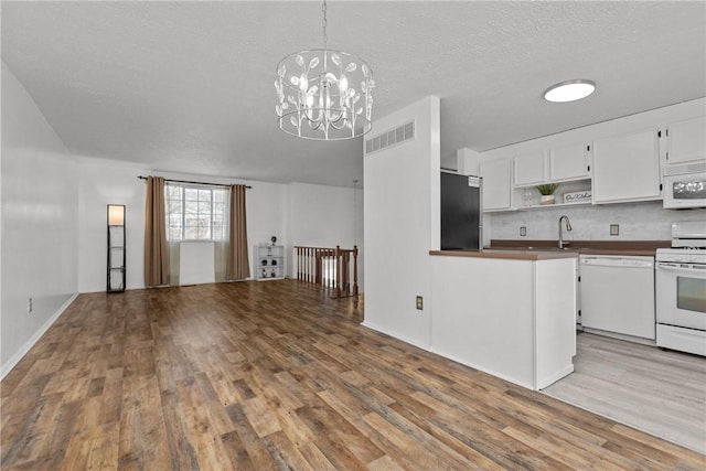 kitchen with white appliances, pendant lighting, wood finished floors, white cabinetry, and open shelves