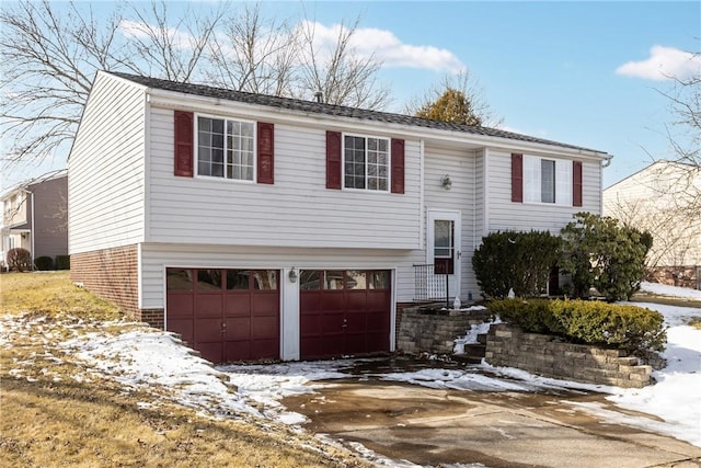 split foyer home featuring an attached garage, driveway, and brick siding