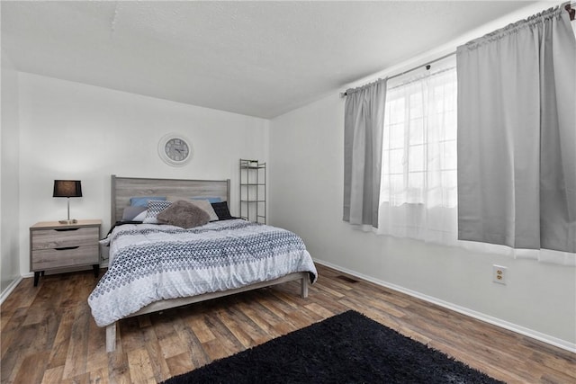 bedroom featuring dark wood-style flooring, visible vents, and baseboards