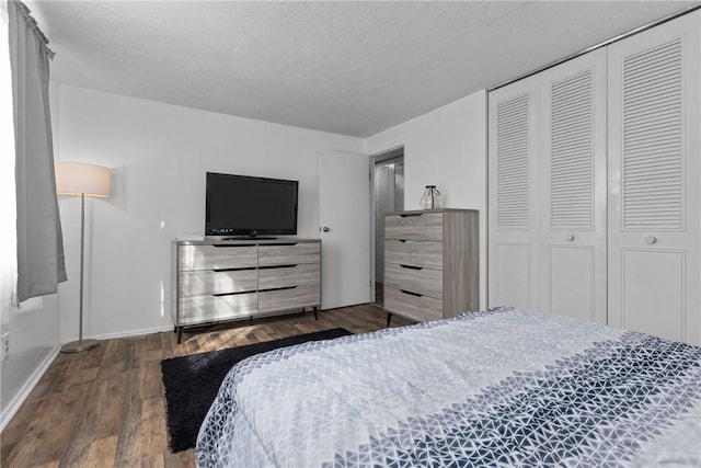 bedroom with a textured ceiling, dark wood-style flooring, a closet, and baseboards