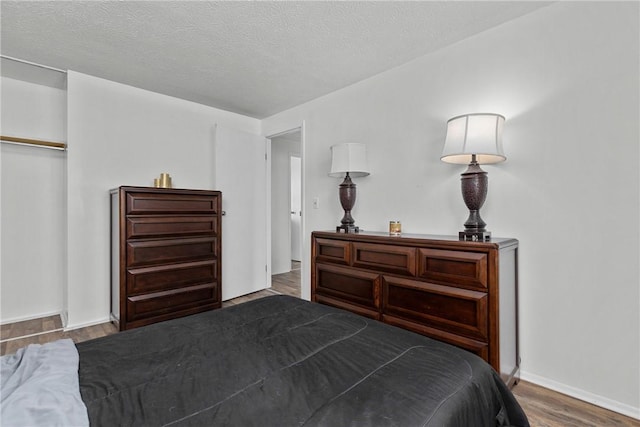 bedroom with dark wood-style floors, a textured ceiling, and baseboards