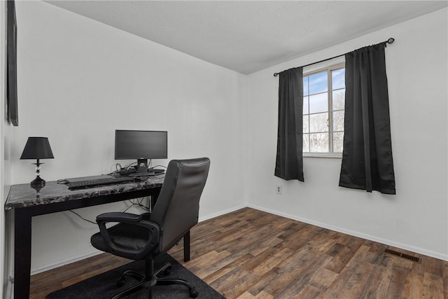 office space with dark wood-style flooring, visible vents, and baseboards