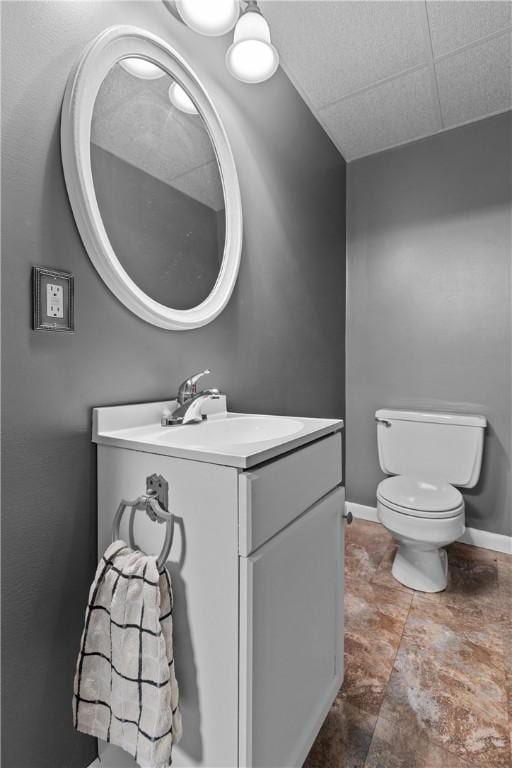 half bathroom with toilet, vanity, and baseboards