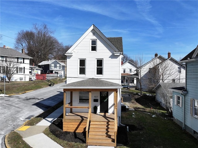 view of front facade featuring a residential view, covered porch, and roof with shingles