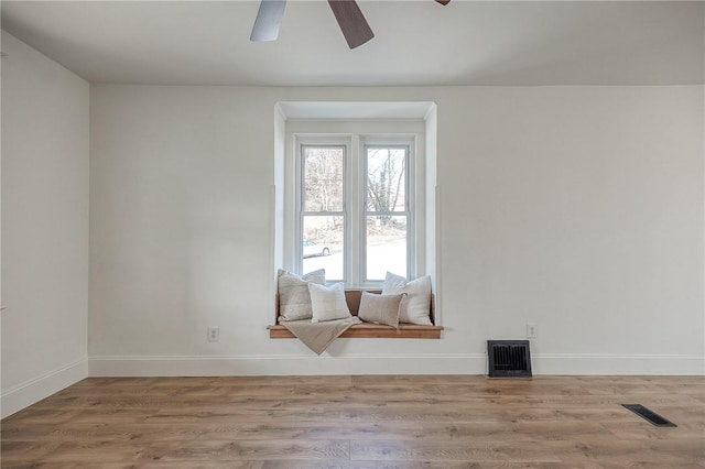 unfurnished room with visible vents, ceiling fan, baseboards, and wood finished floors