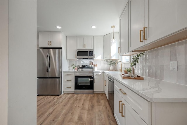 kitchen featuring a sink, white cabinets, appliances with stainless steel finishes, backsplash, and pendant lighting