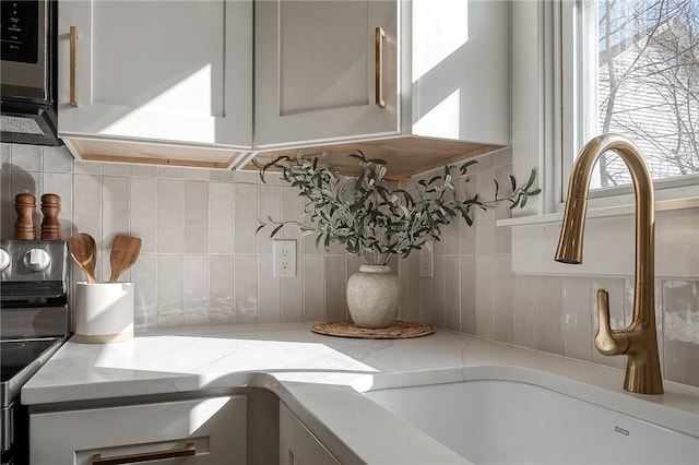 interior space featuring a sink, decorative backsplash, and light stone countertops