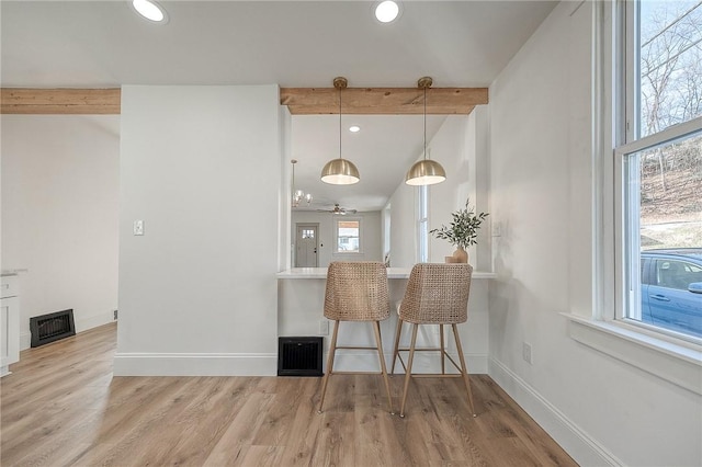 kitchen featuring visible vents, beamed ceiling, hanging light fixtures, and light wood finished floors