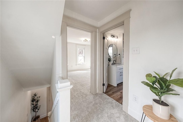 corridor featuring a sink and light colored carpet