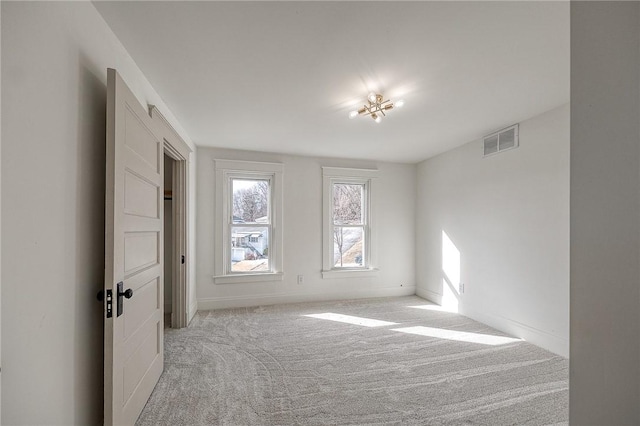 unfurnished room featuring visible vents, light carpet, and baseboards