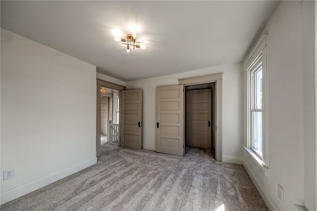 unfurnished bedroom with multiple windows, baseboards, and light colored carpet