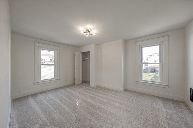 unfurnished bedroom with a closet, light colored carpet, and baseboards