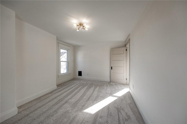 spare room featuring light carpet and baseboards