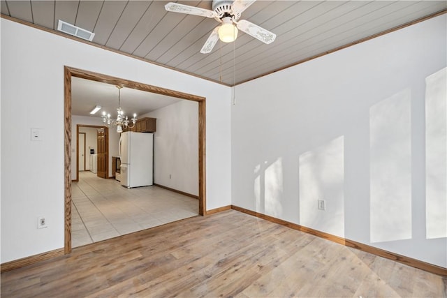 empty room featuring ceiling fan with notable chandelier, visible vents, baseboards, ornamental molding, and light wood finished floors