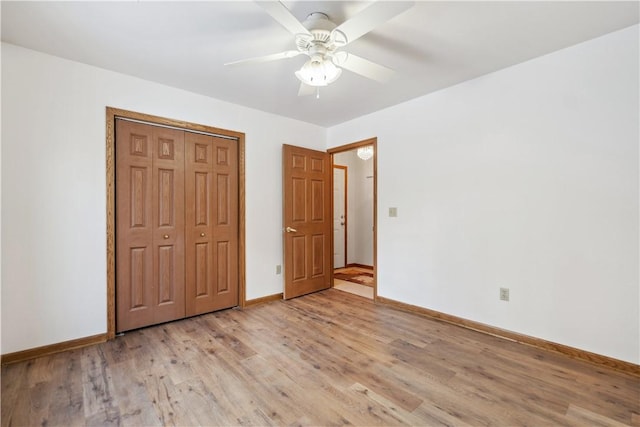 unfurnished bedroom featuring a closet, light wood-type flooring, a ceiling fan, and baseboards