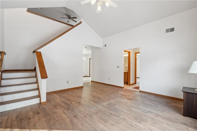 unfurnished living room with light wood finished floors, visible vents, stairway, a ceiling fan, and high vaulted ceiling