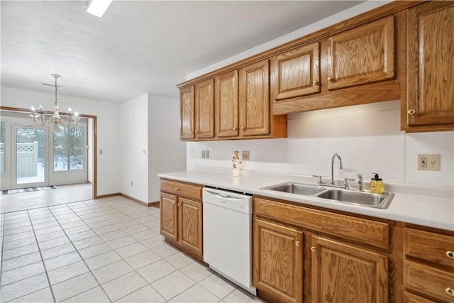 kitchen featuring brown cabinets, hanging light fixtures, white dishwasher, light countertops, and a sink