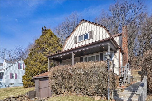 dutch colonial featuring stairway, a chimney, and a gambrel roof