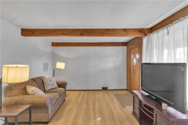 living room featuring light wood-style flooring, visible vents, and beam ceiling