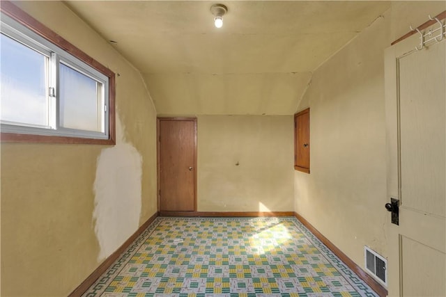 interior space featuring vaulted ceiling, light floors, and baseboards