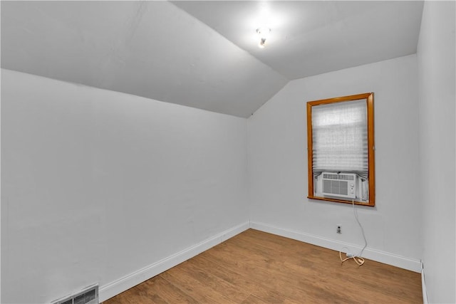 additional living space with lofted ceiling, cooling unit, visible vents, baseboards, and light wood-style floors