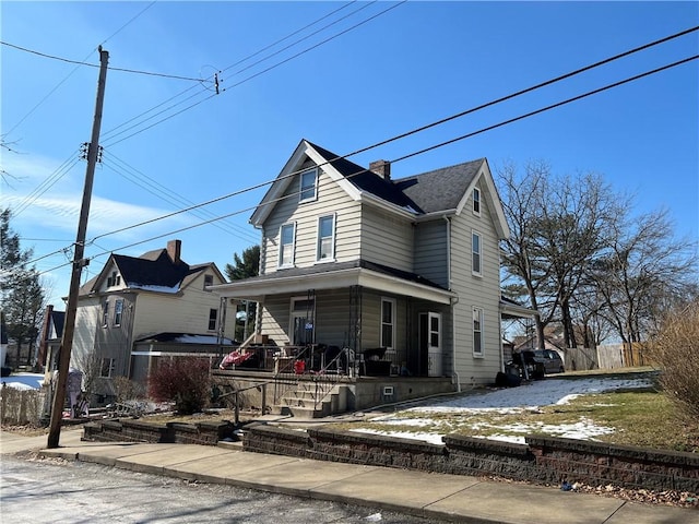 traditional-style house with a porch, fence, and a chimney