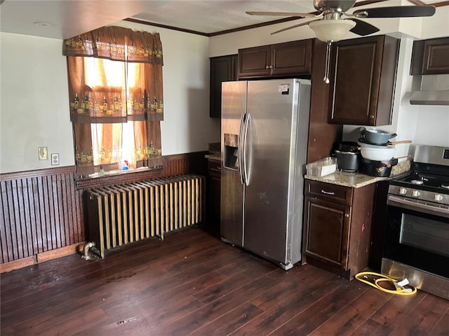 2504 Olympia St, Mckeesport, PA 15132 - kitchen with appliances with stainless steel finishes, radiator heating unit, a wainscoted wall, a ceiling fan, and dark wood-style flooring