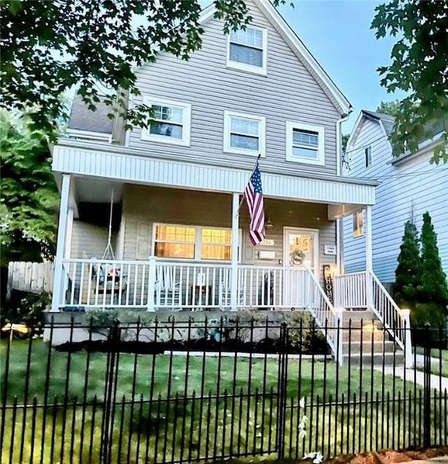 view of front of property featuring covered porch, a front lawn, and a fenced front yard