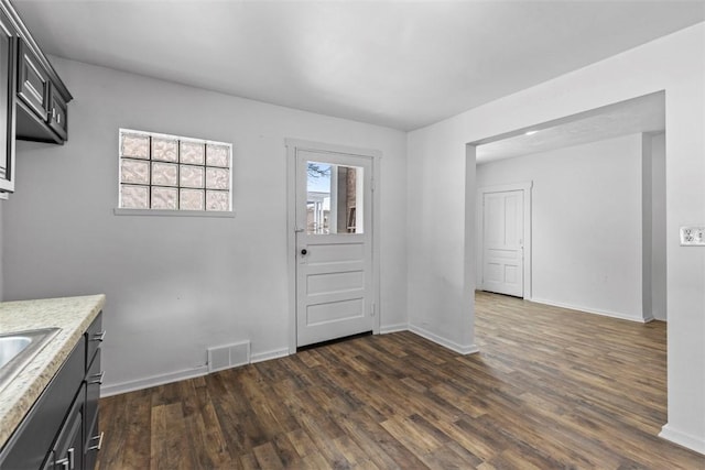 kitchen with baseboards, visible vents, dark wood finished floors, and dark cabinetry