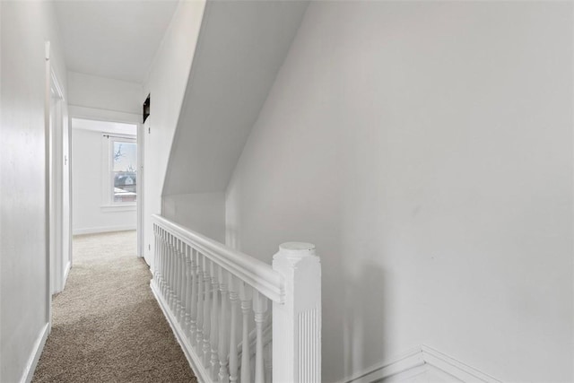 hall with carpet flooring, an upstairs landing, and baseboards