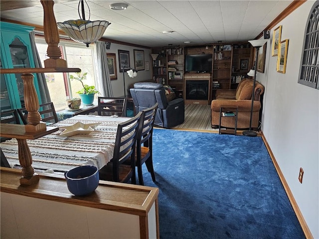 carpeted dining space featuring a fireplace, baseboards, and crown molding