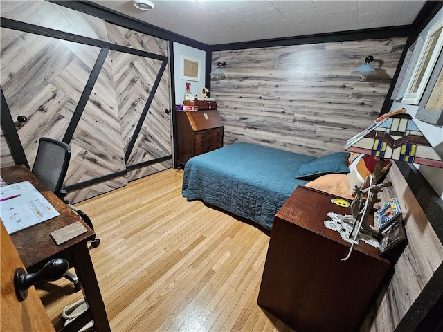 bedroom with light wood-type flooring, wood walls, and crown molding