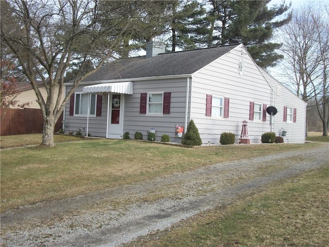 view of front of property with a shingled roof, a chimney, a front yard, and fence