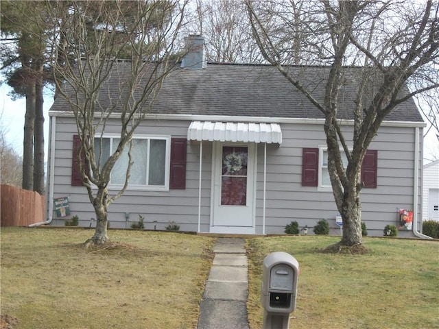 view of front of home featuring a chimney, a front lawn, and roof with shingles