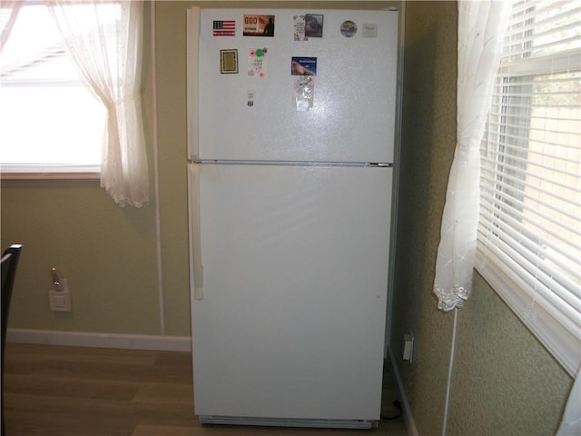 details featuring wood finished floors, freestanding refrigerator, and baseboards