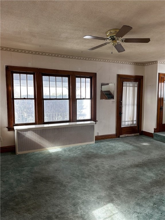 carpeted spare room with baseboards, ceiling fan, a textured ceiling, and radiator heating unit